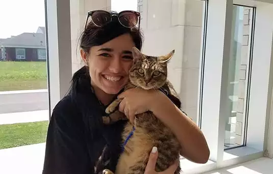 pet owner holding tabby cat in the animal hospital lobby, smiling while hugging pet